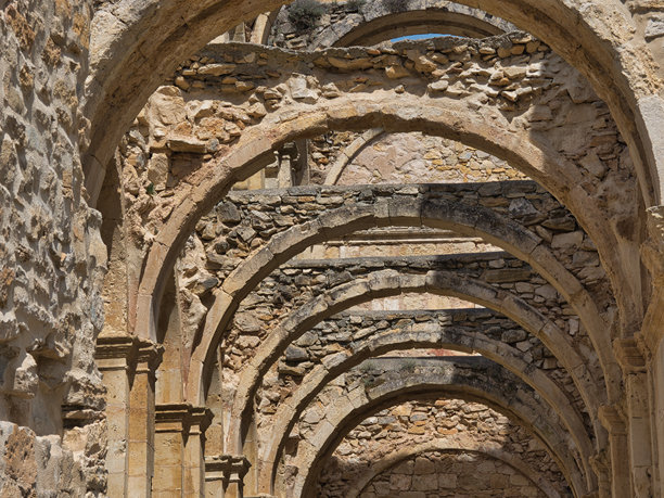 中世纪修道院遗址的拱门 - 哥特式废弃修道院的石拱和石柱，背景是蓝天，坐落在西班牙的山地景观中。图片下载