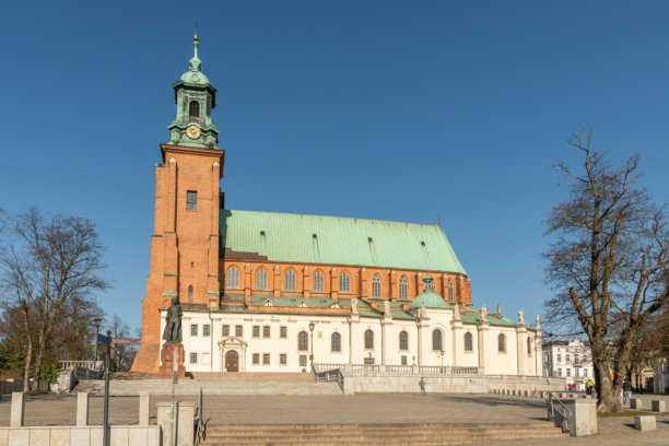 波兰，格涅兹诺。阳光明媚的日子里，格涅兹诺大教堂的景象。照片角落有一些行人，还有一位骑自行车的男士。图片下载