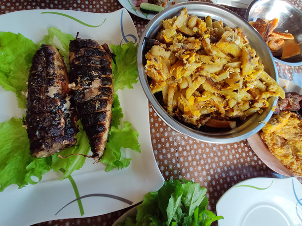 餐桌上的家常午餐：生菜叶烤鱼、鸡蛋煎土豆、炸肉排和煎蛋卷。丰盛而温馨的乡村餐桌。图片下载