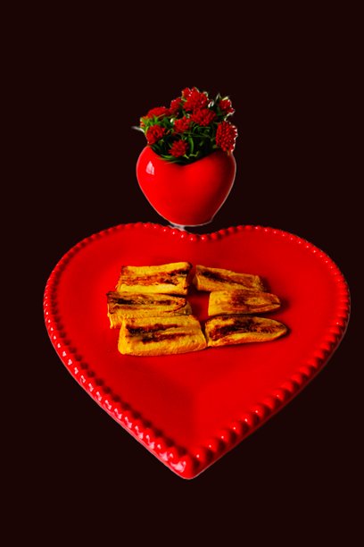 黑色背景上心形盘子里的烤香蕉。竖幅照片，留有复制空间。图片下载