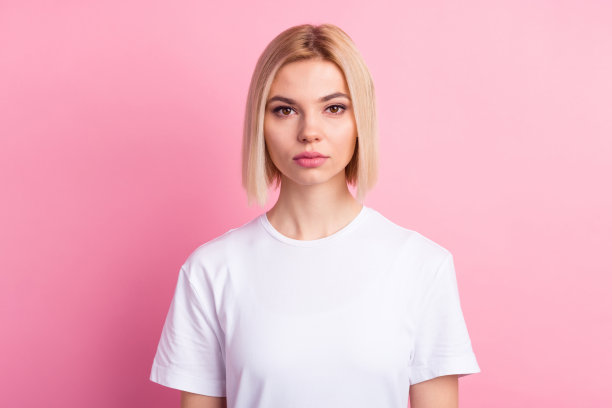 照片：一位年轻美丽的女孩，身着基础款服装，表情专注地看向镜头，背景是淡粉色图片下载