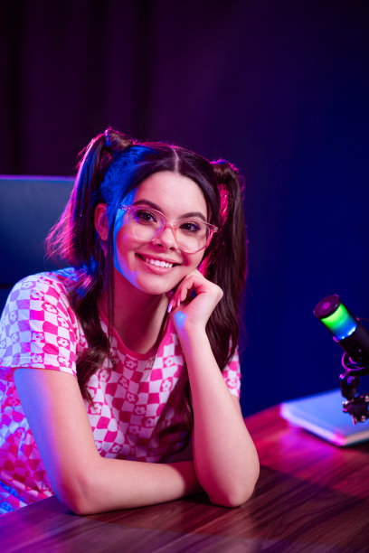 一位年轻的女视频博主在霓虹灯照亮的、配有专业设备的工作室里，以时尚的风格创作数字内容。图片下载