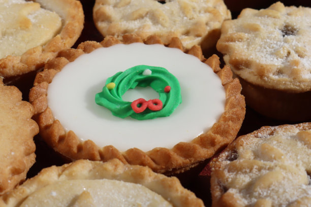 全画幅图片，展示了馅饼，上面装饰着白色的糖霜或糕点星星、雪花或冬青叶图案的盖子，这是节日圣诞甜点，酥皮糕点内含甜馅，撒上糖粉或饰有绿色和红色糖霜的圣诞花环。图片下载