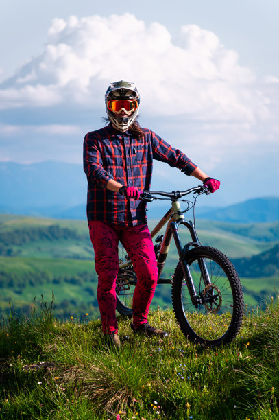 身穿防护装备的运动员在田野中，面朝镜头，背景是雾气弥漫的山脉和积云。山地运动概念。图片下载