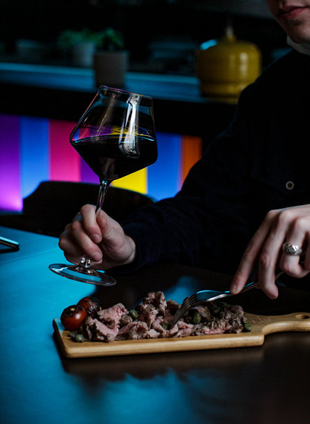 一杯红酒和一份肉类开胃菜，手部特写照片。图片下载