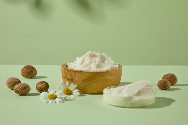 圆木碗中盛有乳木果油，配以洋甘菊和坚果，背景为绿色。非常适合护肤品和水疗产品广告。图片下载