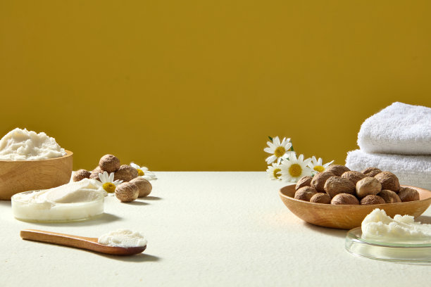 桌上平铺着乳木果油、坚果、洋甘菊花朵和毛巾，这是受水疗启发的、以黄色为背景的健康品牌拍摄照片。图片下载