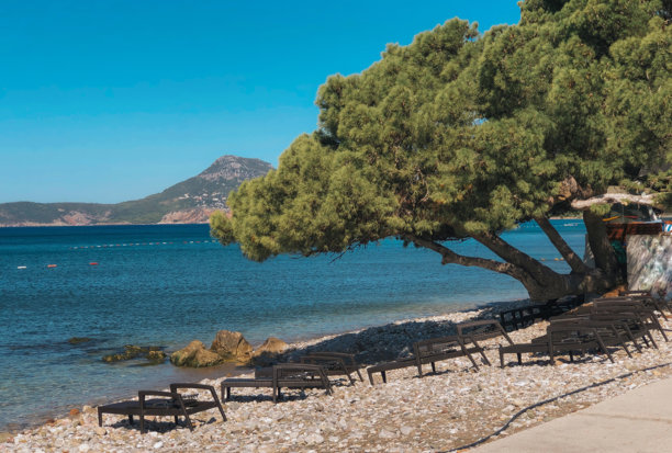 一张明亮、阳光充足的广角照片，捕捉到了地中海海滩上宁静的景象，该海滩位于一个沿海度假区，可能在黑山或克罗地亚。图片下载