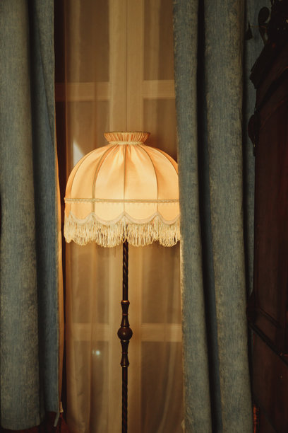 卧室里的美丽灯罩。带有流苏的旧落地灯，上面有一个洞。复古风格的房间装饰，窗边的家具细节和旧灯。老式落地灯。图片下载