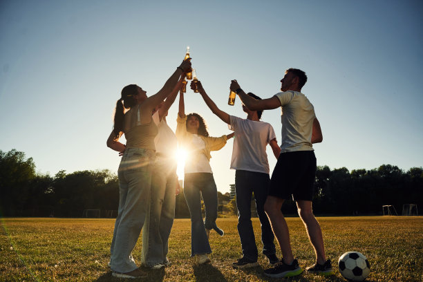 逆光。人们欢呼庆祝、举着啤酒瓶的暗调照片图片下载
