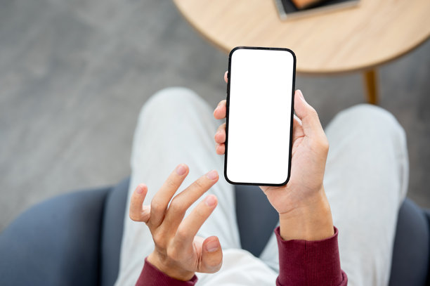 一只手在咖啡馆或图书馆里，手指悬停在持有白色屏幕智能手机的上方图片下载