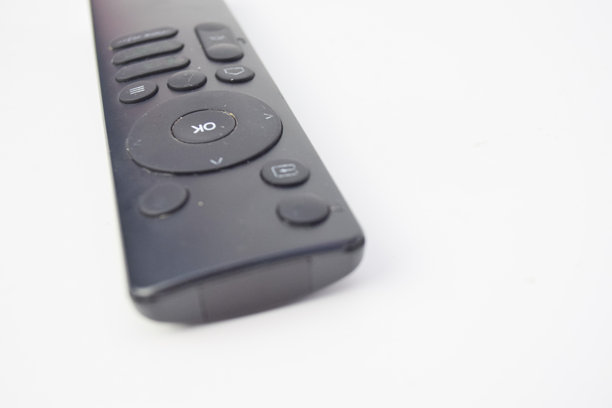 白色背景下的黑色遥控器特写，简约的电子产品照片，展示按钮和纹理，概念用于技术、设备或娱乐控制。图片下载