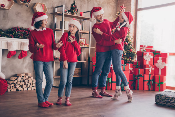 照片：一个快乐友好的家庭正在享受派对，父亲在跳舞，母亲和孩子们在装饰好的圣诞家庭室内交谈图片下载