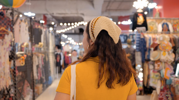 年轻的亚洲Z世代少女，面带笑容，在零废弃、环保、绿色、二手销售、旧货店、跳蚤市场、商场、古着、复古风格的商店里开心旅行。一位年轻女子正在享受购物乐趣。图片下载