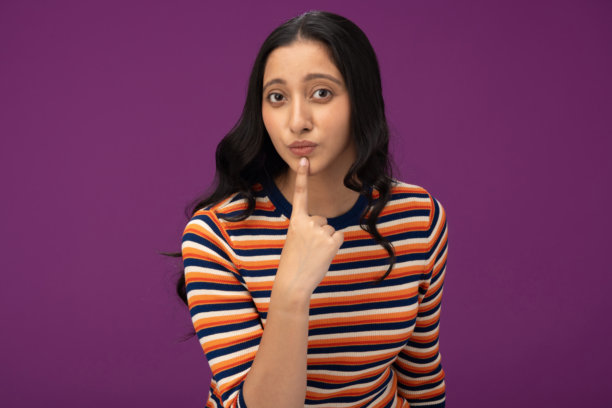 穿着条纹T恤的漂亮年轻女孩照片，孤立在紫色背景上图片下载