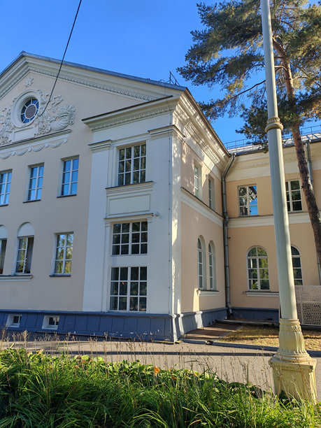 一座宏伟的建筑，带有装饰性浮雕和对称的窗户，周围环绕着茂盛的植物。这张照片捕捉了自然与建筑遗产的和谐融合。图片下载