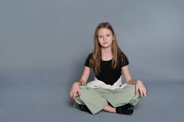 一个女孩随意地坐在地上，姿势放松。这张图片反映了真实的青春时刻，常与情感发展和自我表达联系在一起。图片下载