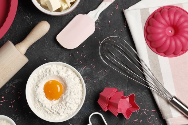 烘焙用具和配料，彩色硅胶烹饪用具、擀面杖、饼干模具、纸杯蛋糕盒和糖洒在深色背景上图片下载