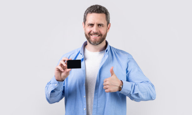 快乐的男人拿着商业借记卡。一个男人拿着商业借记卡的照片。男人展示商业借记卡。图片下载