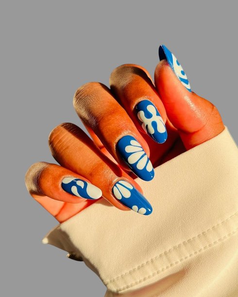 年轻女性的手，拥有光滑的棕色皮肤，展示着优雅现代的美甲和创意手绘美甲设计图片下载