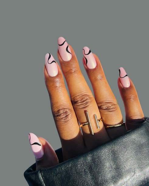 年轻女性的双手，拥有光滑的棕色皮肤，展示着优雅的现代美甲和创意手绘美甲设计图片下载