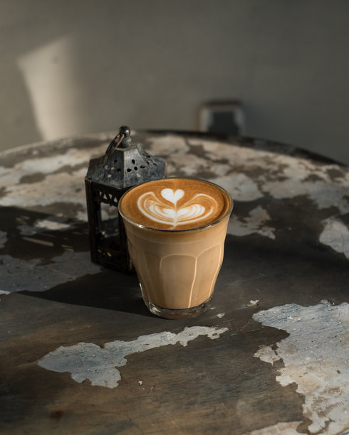 在质朴的氛围中享用美味的拿铁咖啡，上面有着漂亮的拉花，完美契合咖啡爱好者的需求和咖啡馆的氛围，呈现温暖的光线和复古风格。图片下载