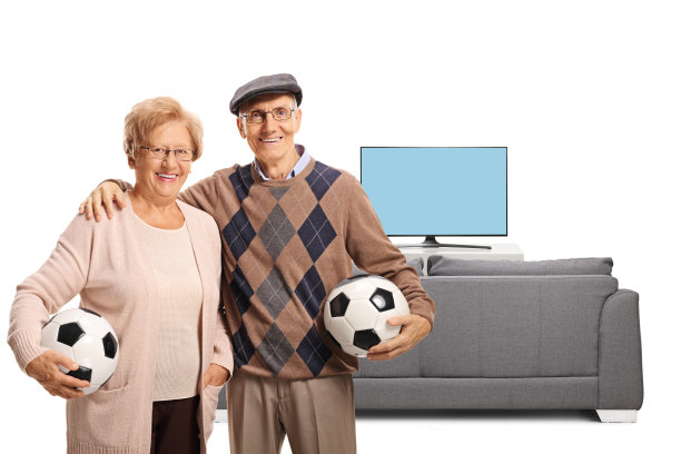 一对老年夫妇在电视和沙发前拿着足球图片下载