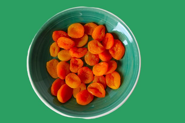 淡绿色背景上放着一个绿色的陶瓷盘子，盘子里盛着一个有机杏子。横幅照片，留有文字空间。图片下载