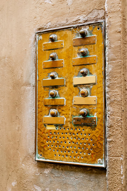 风化复古黄铜或铜制门铃对讲面板，带有空白姓名牌和按钮，安装在欧洲城市旧抹灰墙上，细节特写图片下载