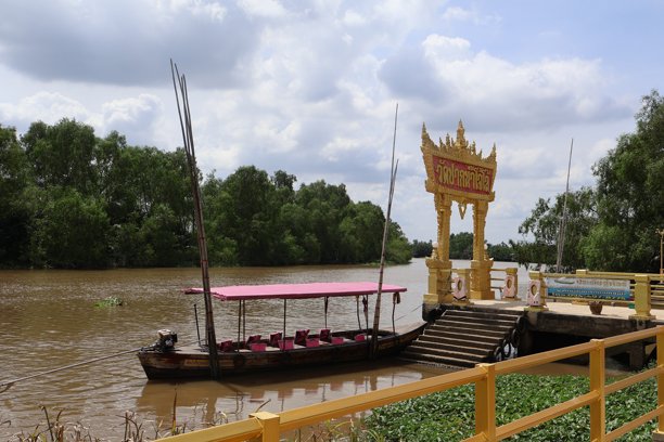 一艘质朴的河流船只，在平静的水面上，木制船身点缀着黄色装饰，周围环绕着郁郁葱葱的绿植，是旅行或休闲主题的理想素材。图片下载