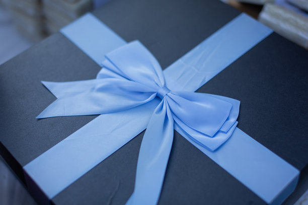 蓝色布艺蝴蝶结系在礼品盒上，特写照片图片下载