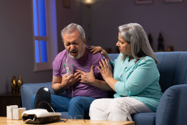 老年夫妇在家中沙发上使用医疗设备测量血压，注意健康库存照片图片下载