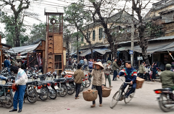 1995年3月18日，越南首都河内历史悠久的旧城区的街景彩色历史照片，展示了一名行人与一名骑自行车者之间的一次惊险的差点碰撞。图片下载
