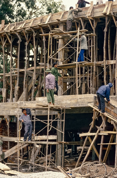 越南河内，1995年3月25日，一座住宅建筑主体结构的木制脚手架上，正在工作的建筑工人留下的历史彩色照片图片下载