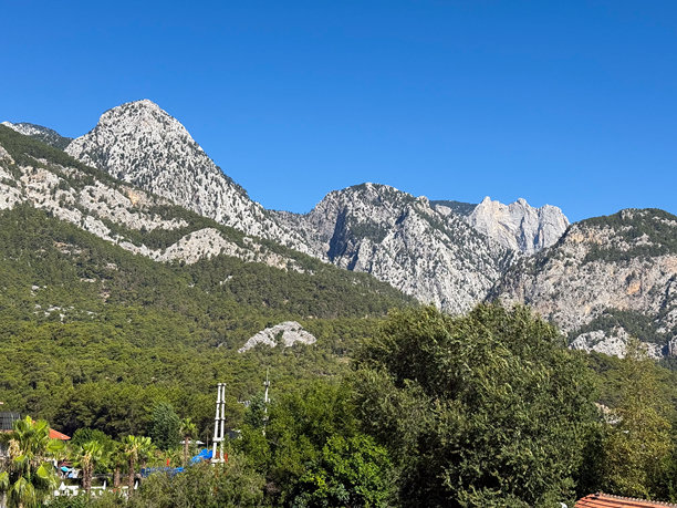 山地景观，拥有岩石山峰、森林斜坡和蓝色的夏日天空。自然、荒野、地质、户外环境和风景全景。图片下载
