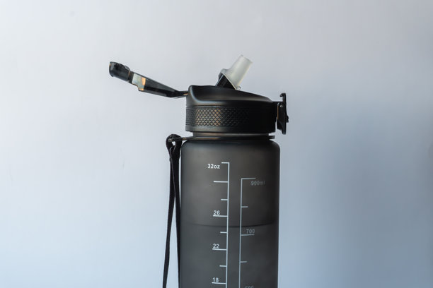 特写照片：一个哑光黑色的32盎司/900毫升可重复使用的水壶，带有刻度线，配有敞开的翻盖吸管盖，孤立在白色背景上。图片下载
