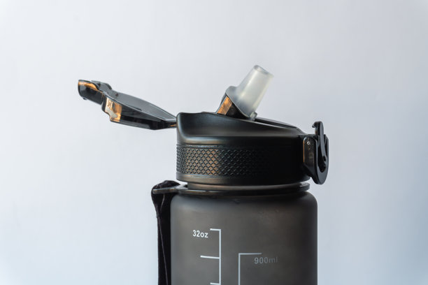 可重复使用的哑光保温瓶，打开的黑色翻盖、安全锁扣和透明吸管嘴的详细特写照片，孤立在白色背景上。图片下载