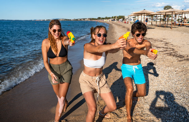 年轻的朋友们在沙滩上玩水枪图片下载