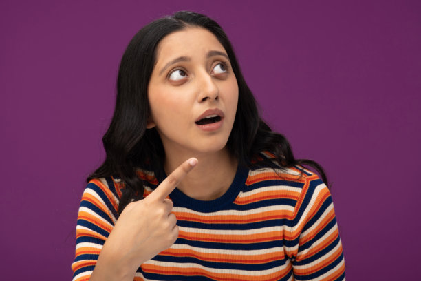 身穿条纹T恤的漂亮年轻女孩，孤立在紫色背景上的素材照片图片下载