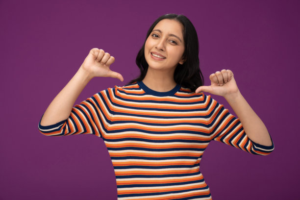 穿着条纹T恤的漂亮年轻女孩照片，孤立在紫色背景上图片下载