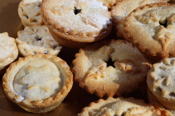 俯视角度拍摄的全画幅金色盛器，里面盛放着堆叠的肉馅饼，顶部饰有翻糖制成的星星、雪花或冬青叶图案，这些节日圣诞甜点是酥皮馅饼，内含甜美的肉馅，并撒上了糖粉。图片下载