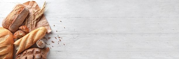一张全景照片，展示了乡村风格的手工面包和麦穗，摆放在白色风化的木桌左侧，留有充足的复制空间。图片下载