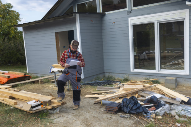 一名男性建筑工人正在建造中的木屋户外工地查看图纸图片下载