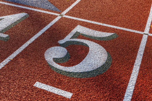 户外跑道跑道车道特写照片，白色数字五，5，带有绿色阴影，在带有白色车道线的全新红色跑道上。图片下载