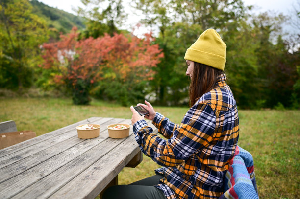女人在秋季野餐时用智能手机拍摄食物照片图片下载