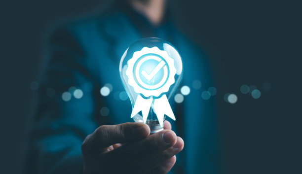商务人士手持发光的灯泡，上面带有质量保证认证徽章和打勾图标，象征着创新、信任、高标准以及商业成功和品牌卓越。图片下载