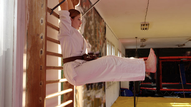 身着空手道服的女性在训练前于体操房的龙门架上做仰卧起坐图片下载