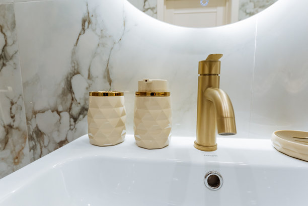 一个带金色水龙头和镜子的浴室洗手池图片下载