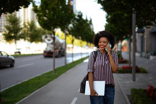 女人在人行道上边走边打电话的素材图片图片下载
