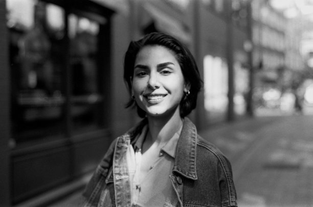 年轻女子在城市环境中微笑，复古颗粒感的黑白模拟照片图片下载